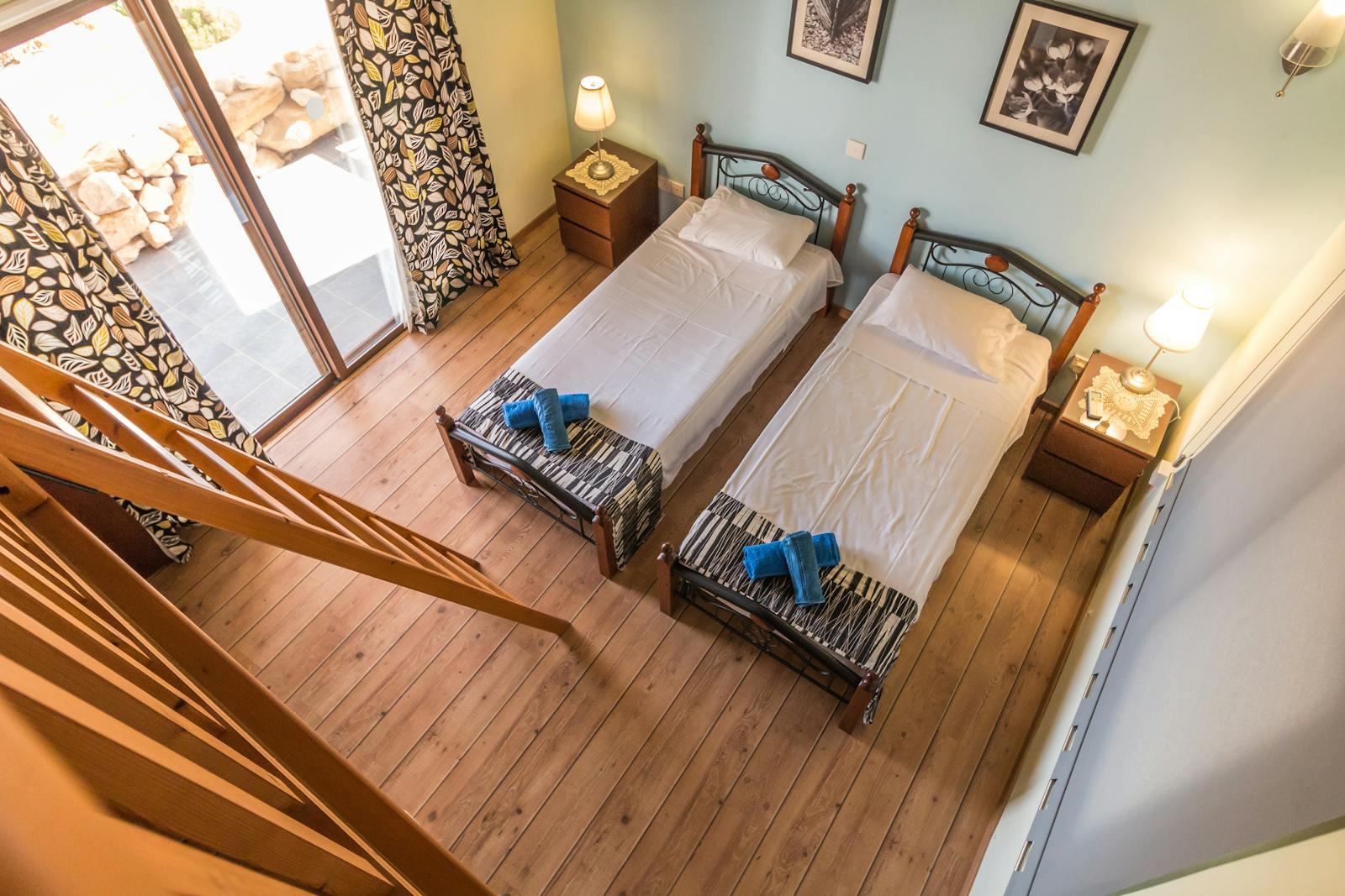 Photo by Pixabay Aerial view of a rustic bedroom with twin beds and wooden decor, featuring a balcony view.